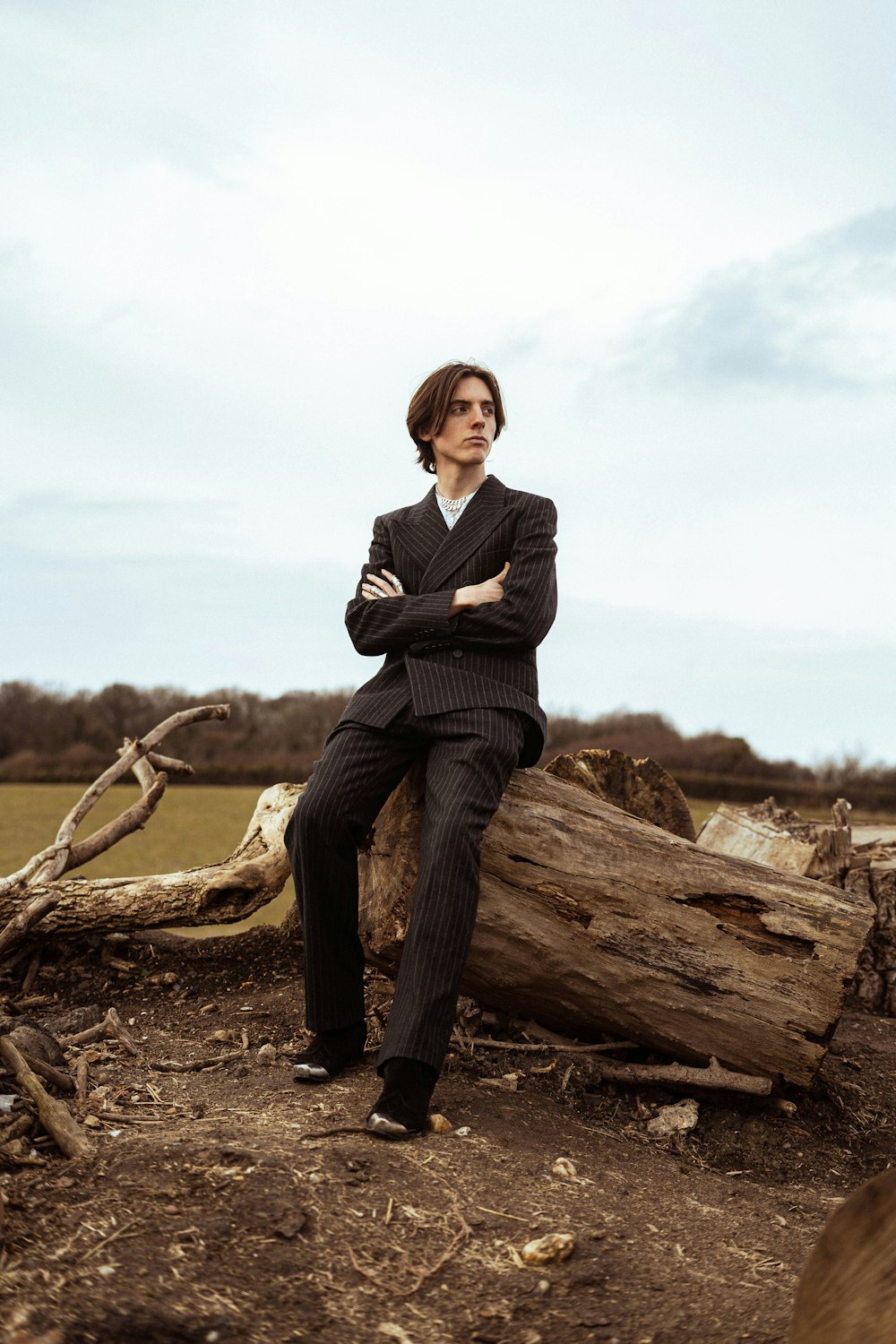 a man in a suit sitting on a log