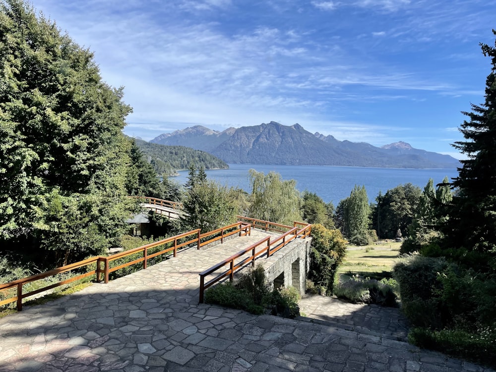 a stone walkway leading to a lake with mountains in the background