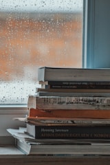 a stack of books sitting on top of a window sill