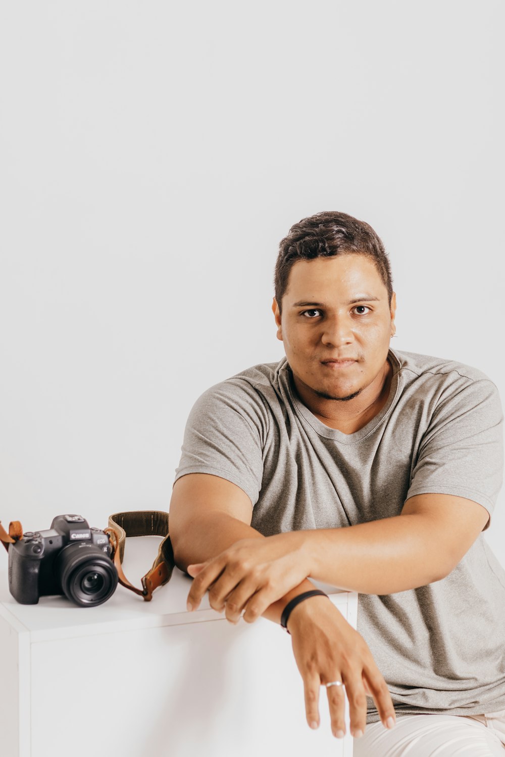 a man sitting on top of a white table next to a camera