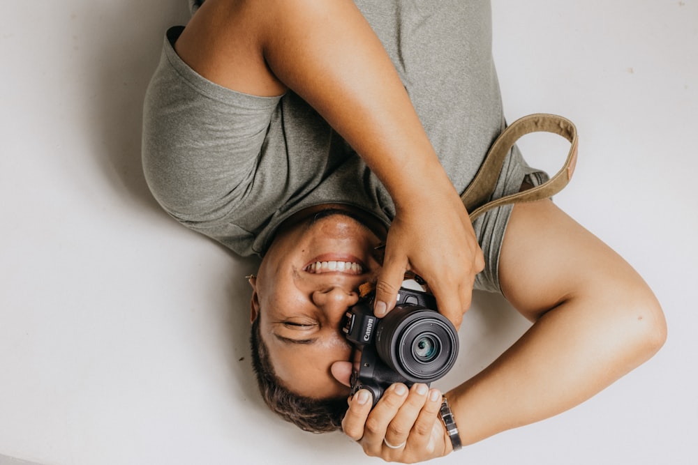 a woman laying on the ground holding a camera