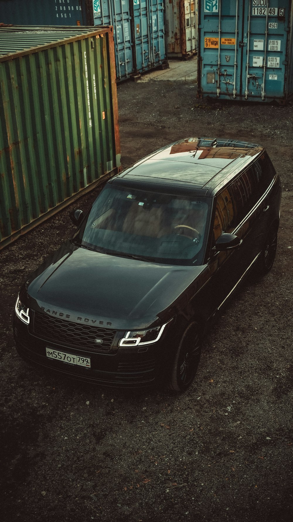 a black car parked in front of a bunch of shipping containers