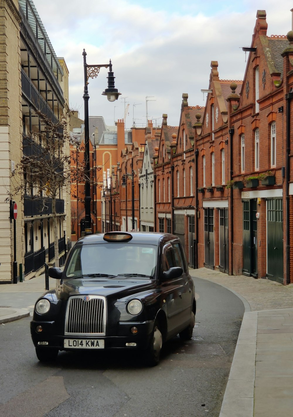 a black taxi cab driving down a street next to tall buildings