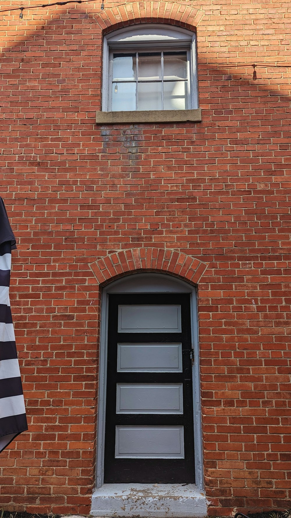 a brick building with a black door and a black and white flag