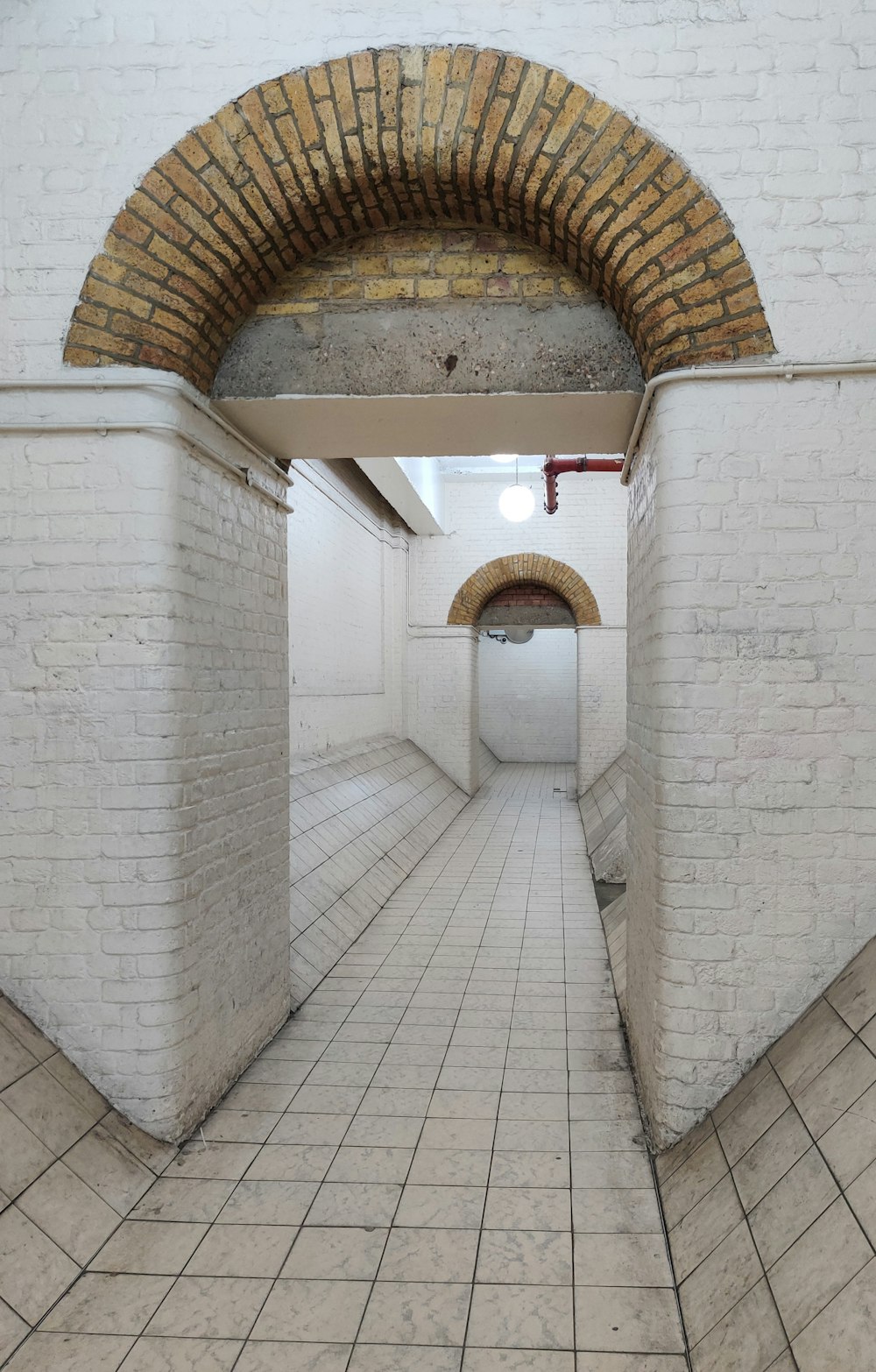 a long narrow hallway with a brick archway