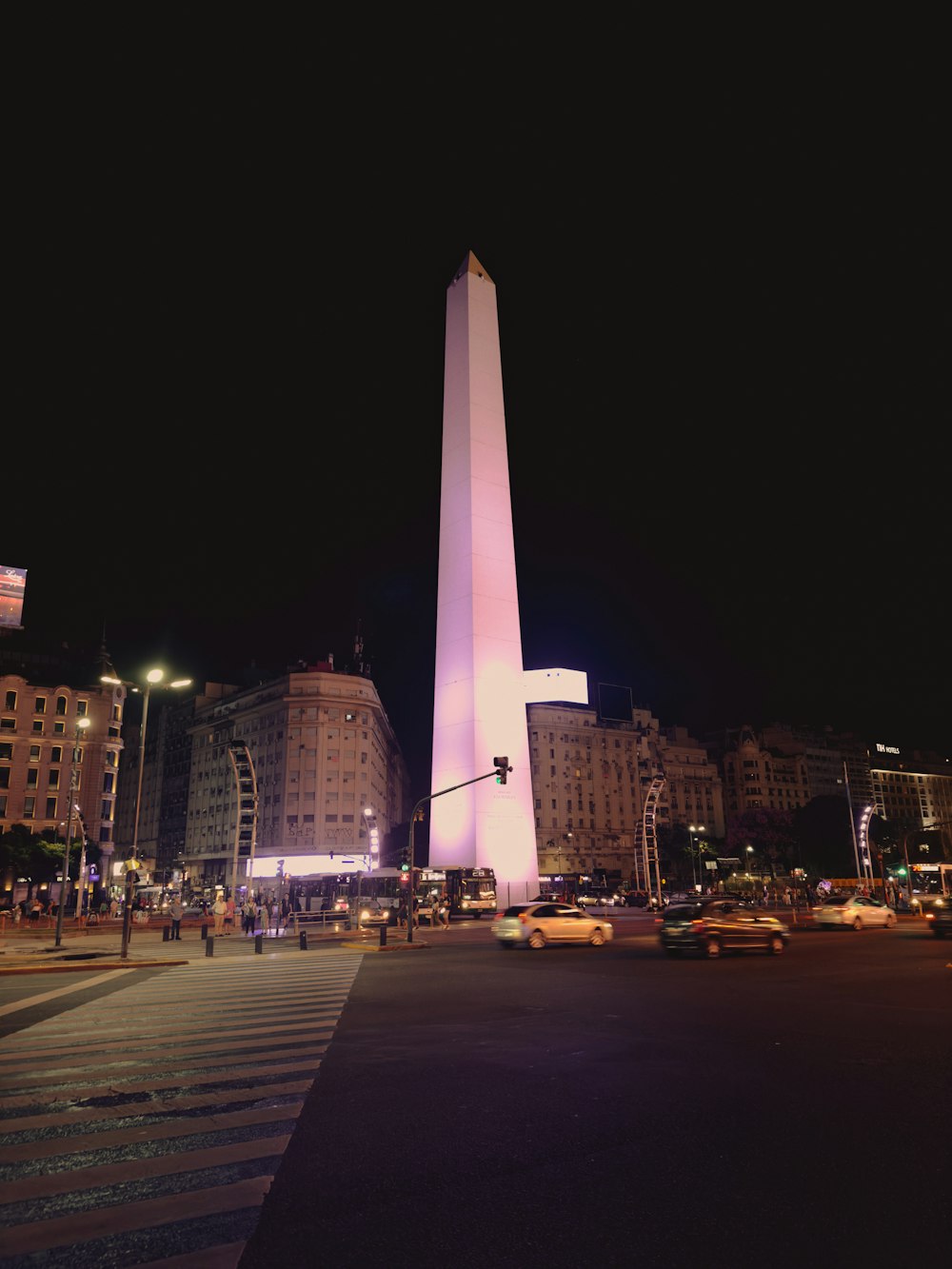 a tall obelisk lit up at night in a city