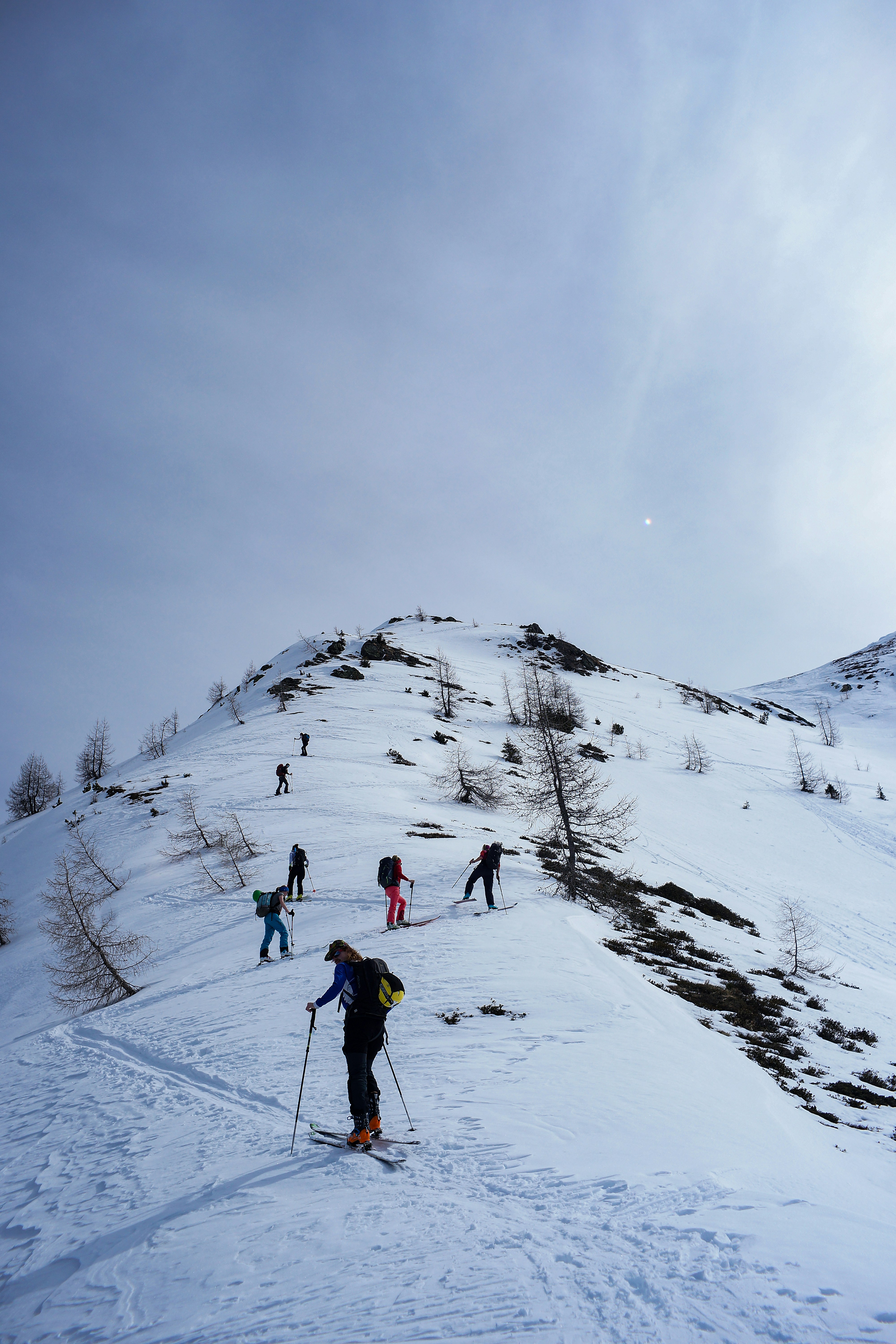 Eine Gruppe von Leuten, die auf Skiern einen schneebedeckten Hang hinunterfahren