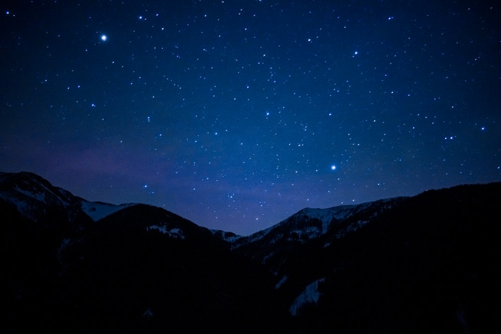 the night sky with stars above the mountains