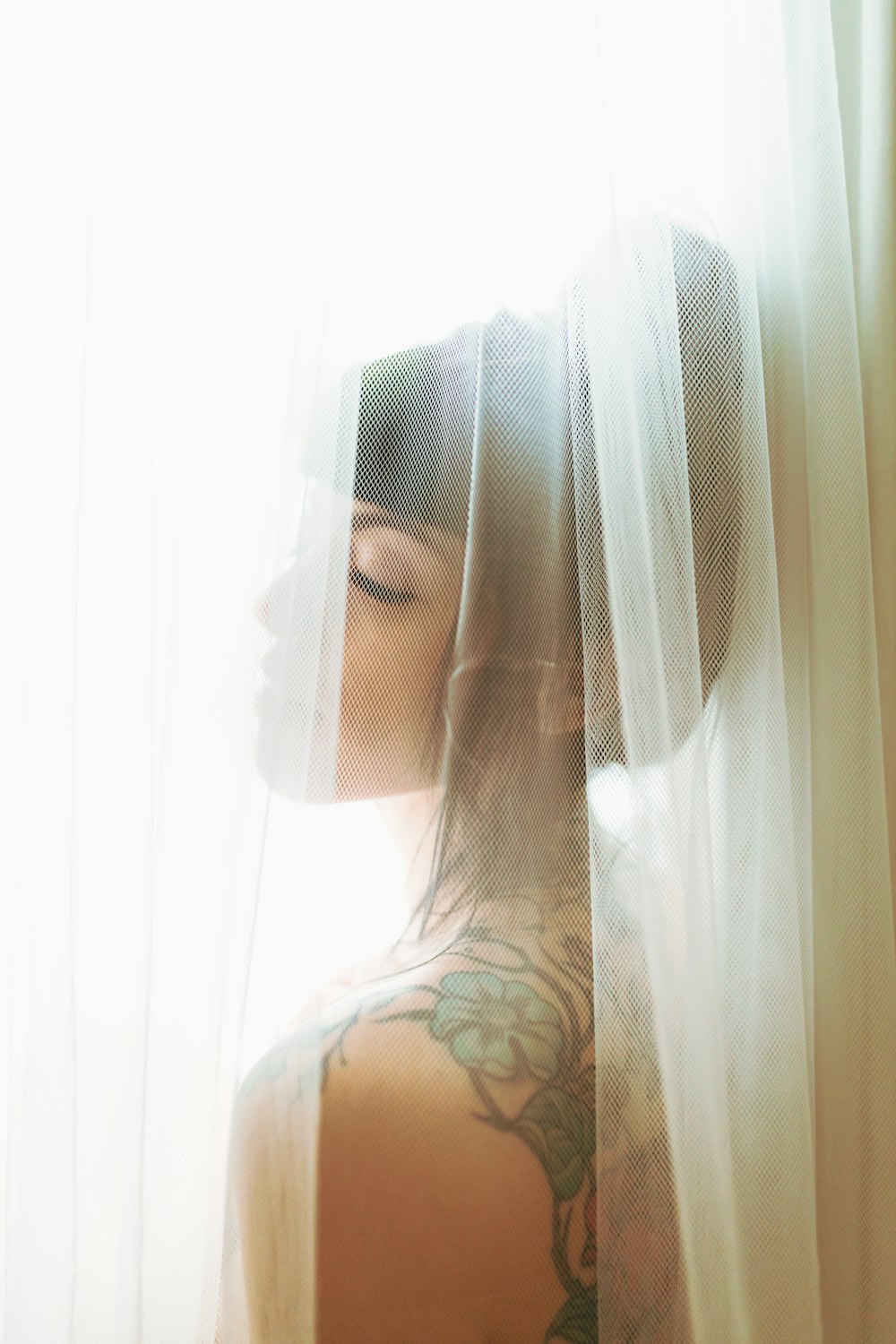 a woman with a tattoo on her back standing in front of a window