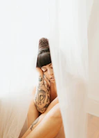 Shyra sitting peacefully in her tattoo studio, surrounded by warm tones and art.
