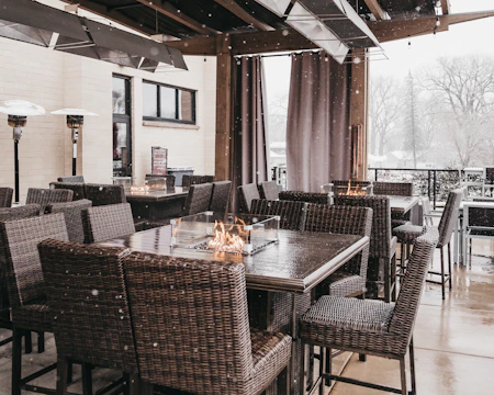 A cozy patio setup with string lights, comfy chairs, and a small fire pit.