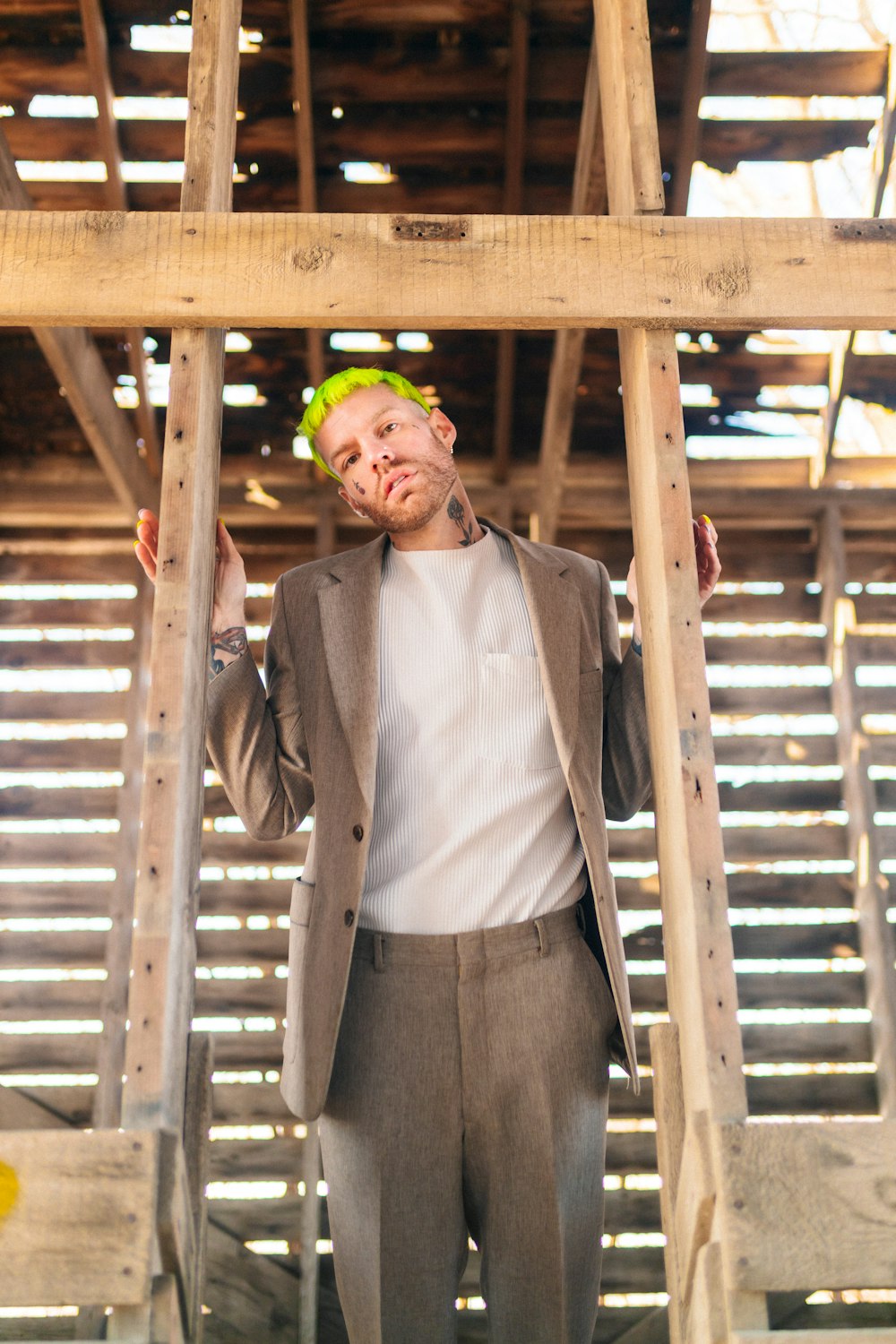 a man in a suit and tie standing under a wooden structure