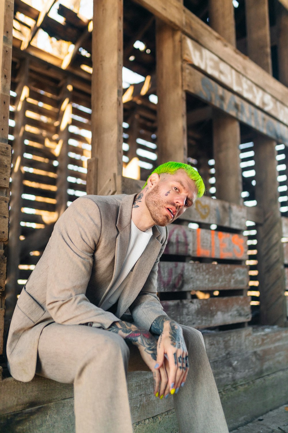 a man with green hair sitting on a wooden bench