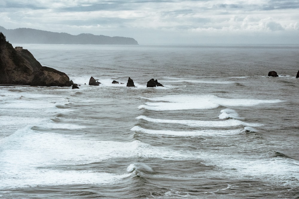 a group of rocks sitting on top of a beach next to the ocean