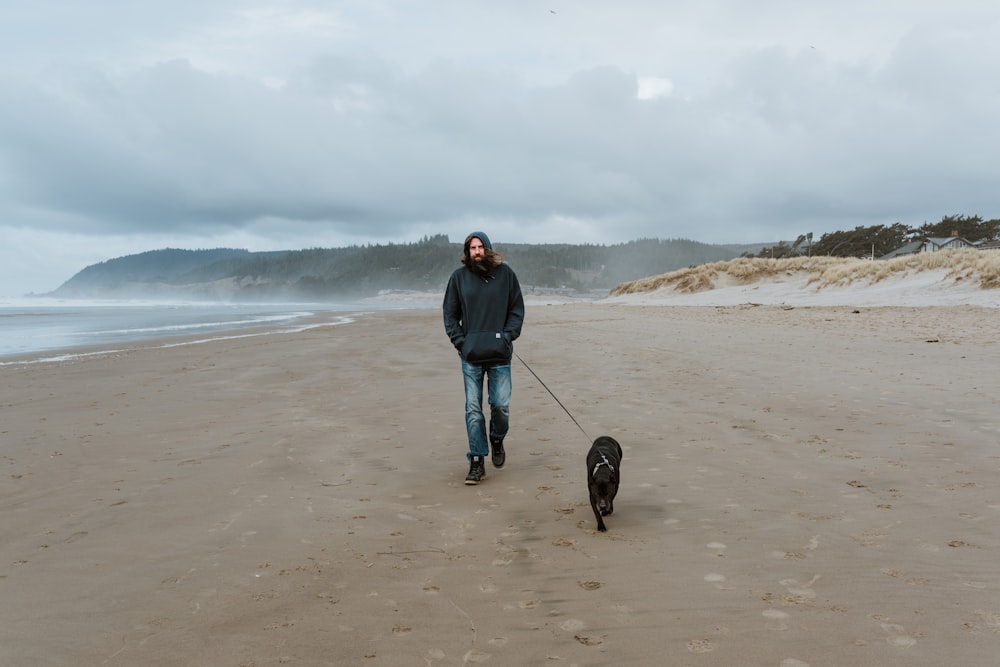 a man walking a dog on a beach