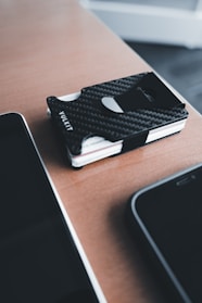 A sleek, minimalist leather wallet resting on a polished wooden desk with soft natural light.