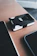 Close-up of a minimalist black Stowly wallet resting on a wooden desk with soft natural light.