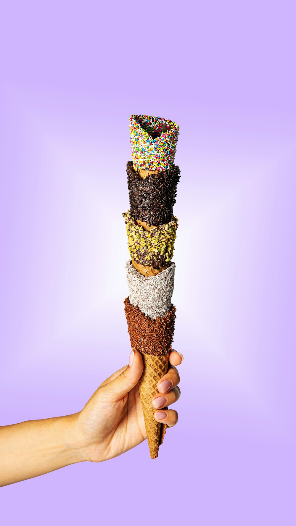 a hand holding an ice cream cone filled with sprinkles