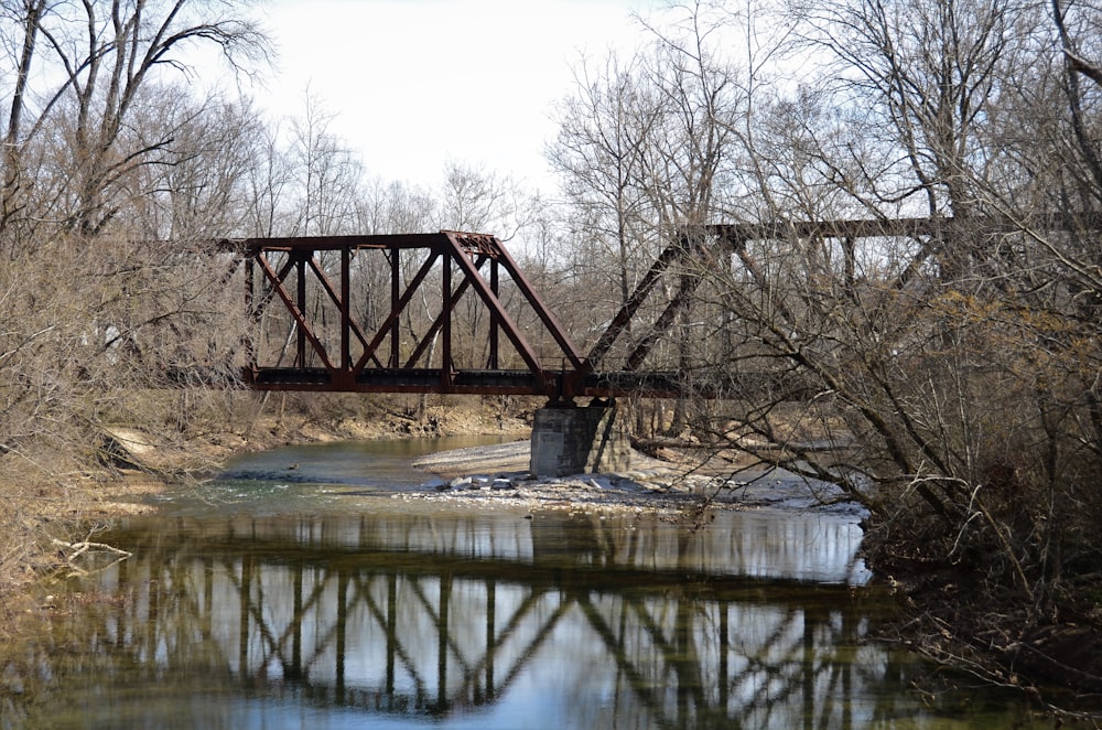 a rusty bridge over a river in a wooded area