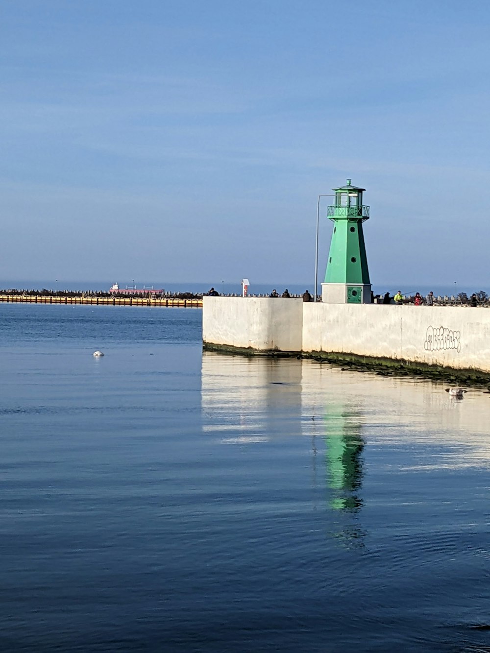 a green light house sitting on top of a pier