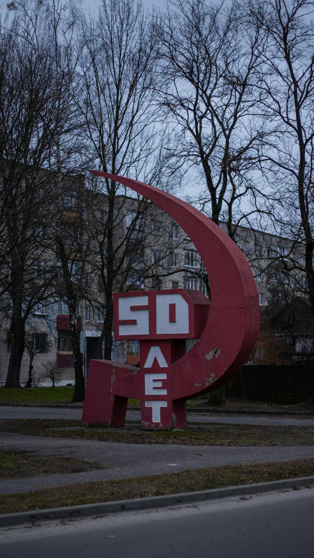 a large red sculpture sitting on the side of a road