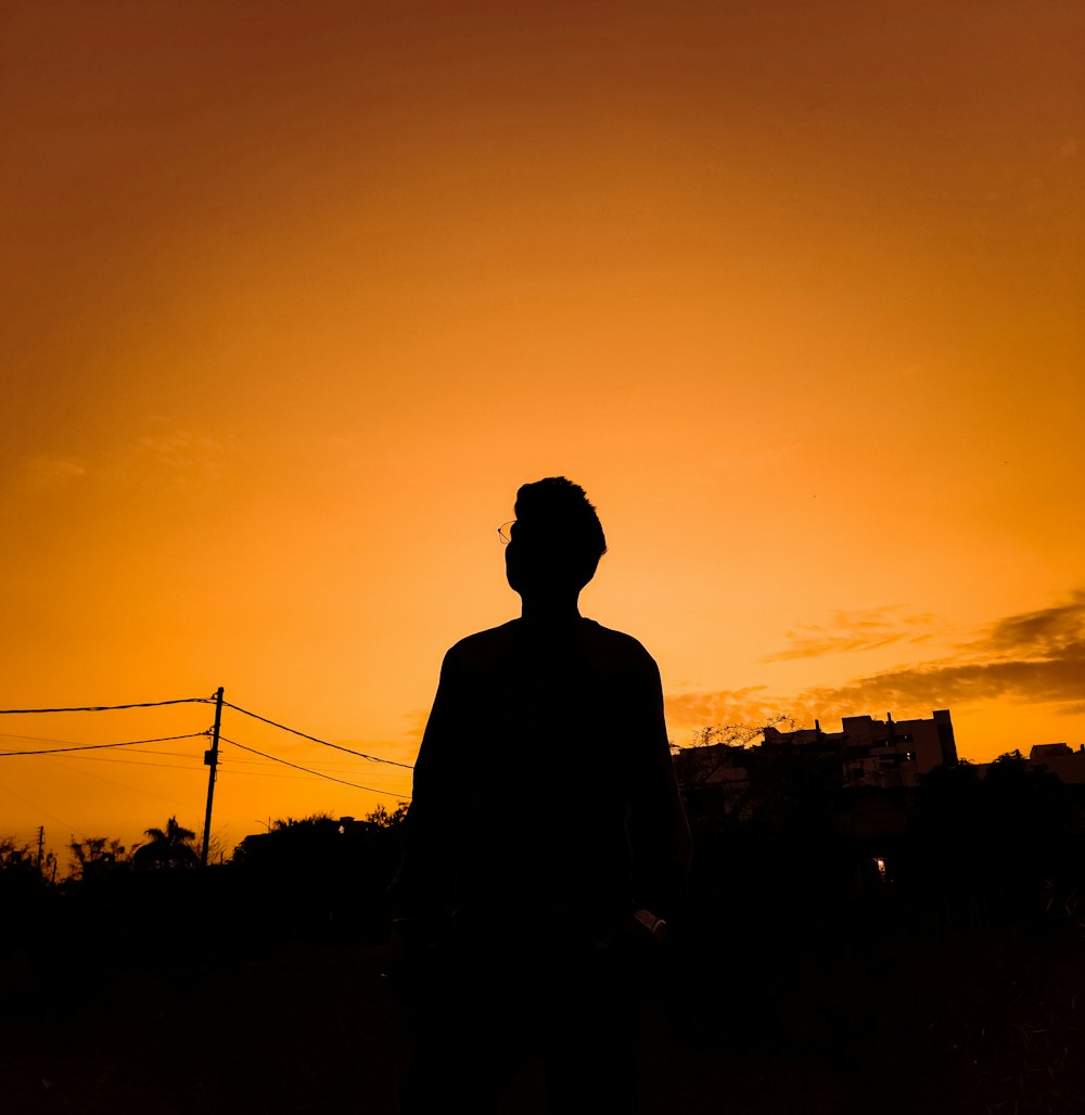 a silhouette of a man standing in front of a sunset