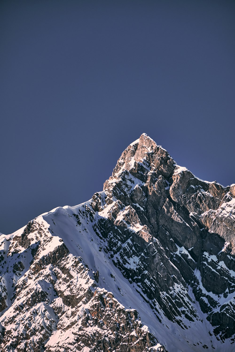 a very tall mountain covered in snow under a blue sky