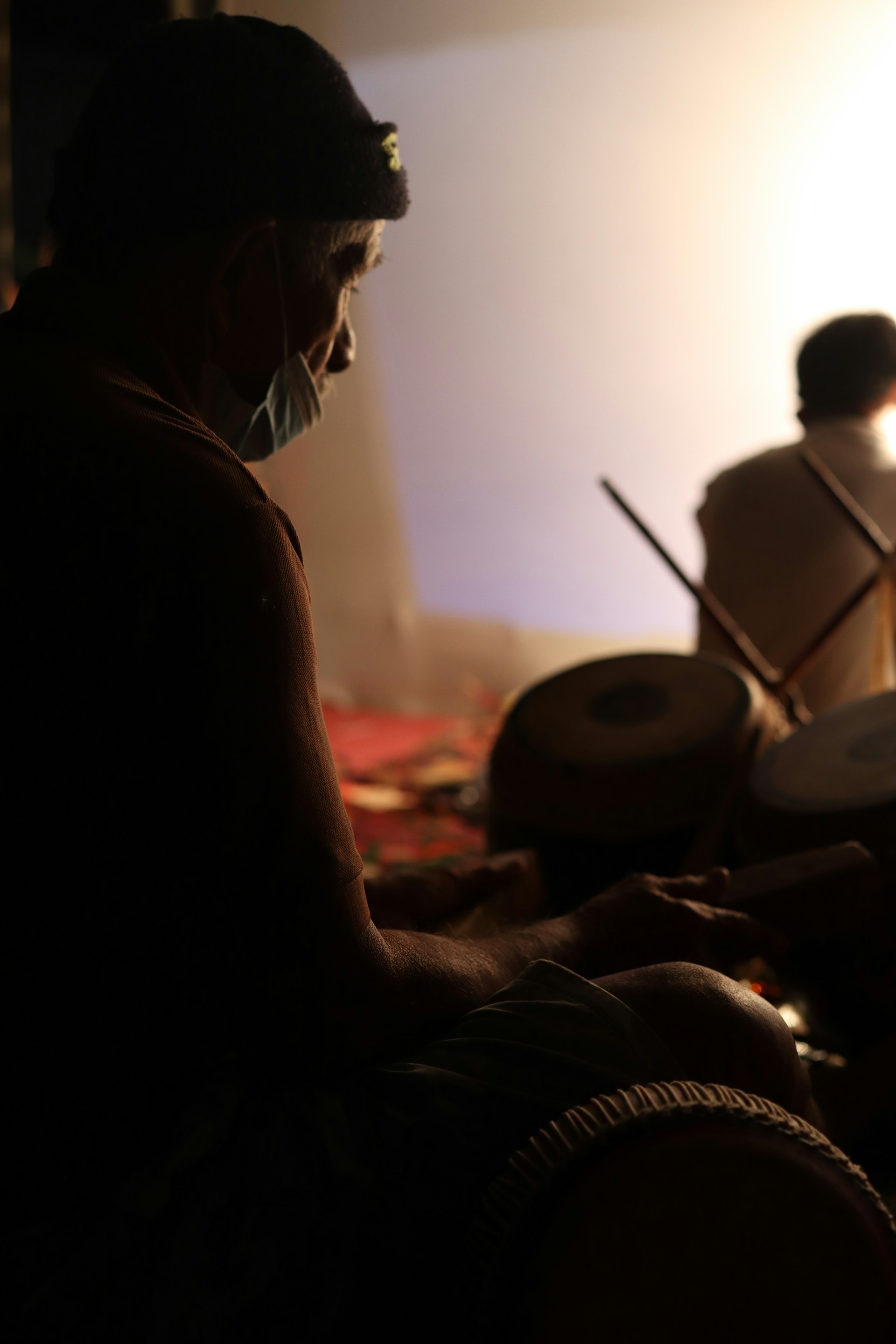 Close-up of a skilled musician passionately playing traditional percussion instruments during an intimate cultural concert.
