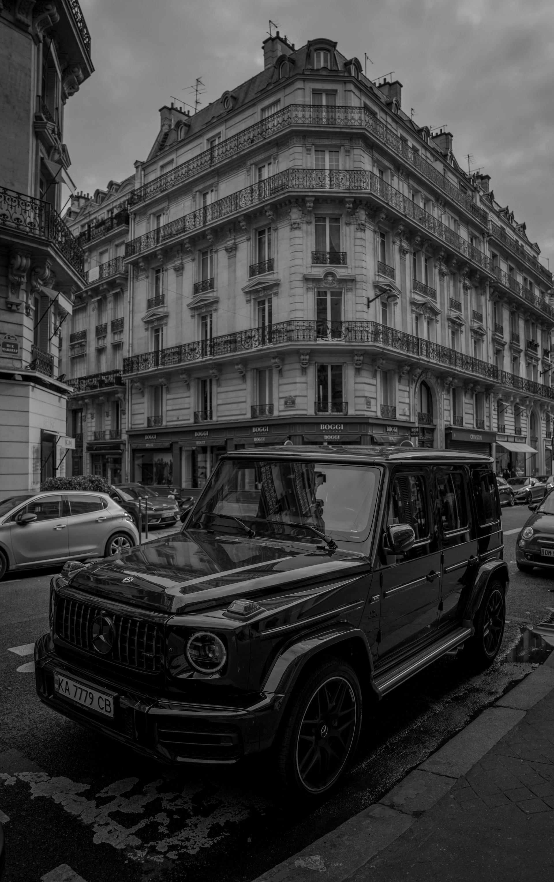 a black and white photo of a jeep parked in front of a building