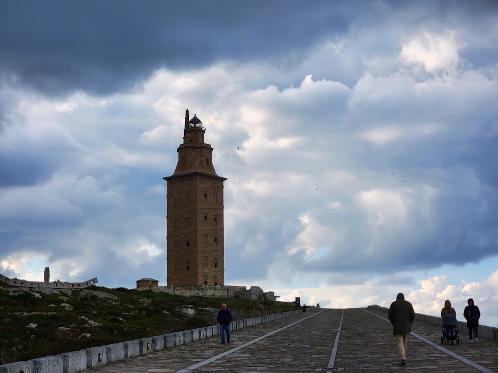 a group of people walking down a road next to a tall tower