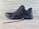 A black athletic shoe with a rugged sole and mesh detailing, designed for outdoor activities. It features brand markings on the side and is positioned against a light wooden background.