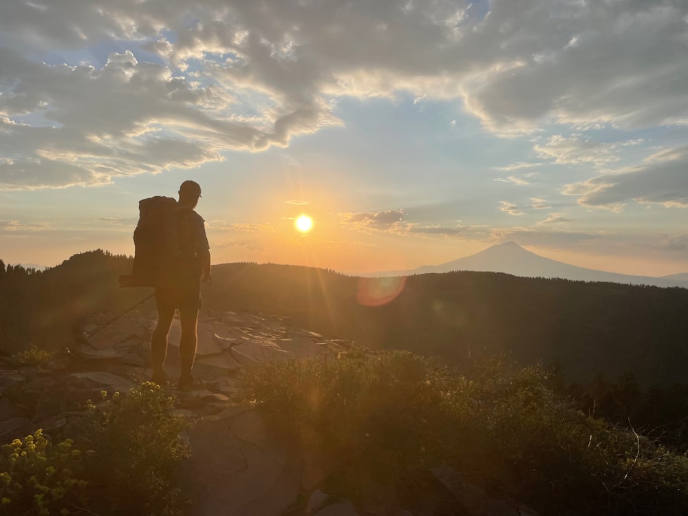 a man standing on top of a mountain at sunset