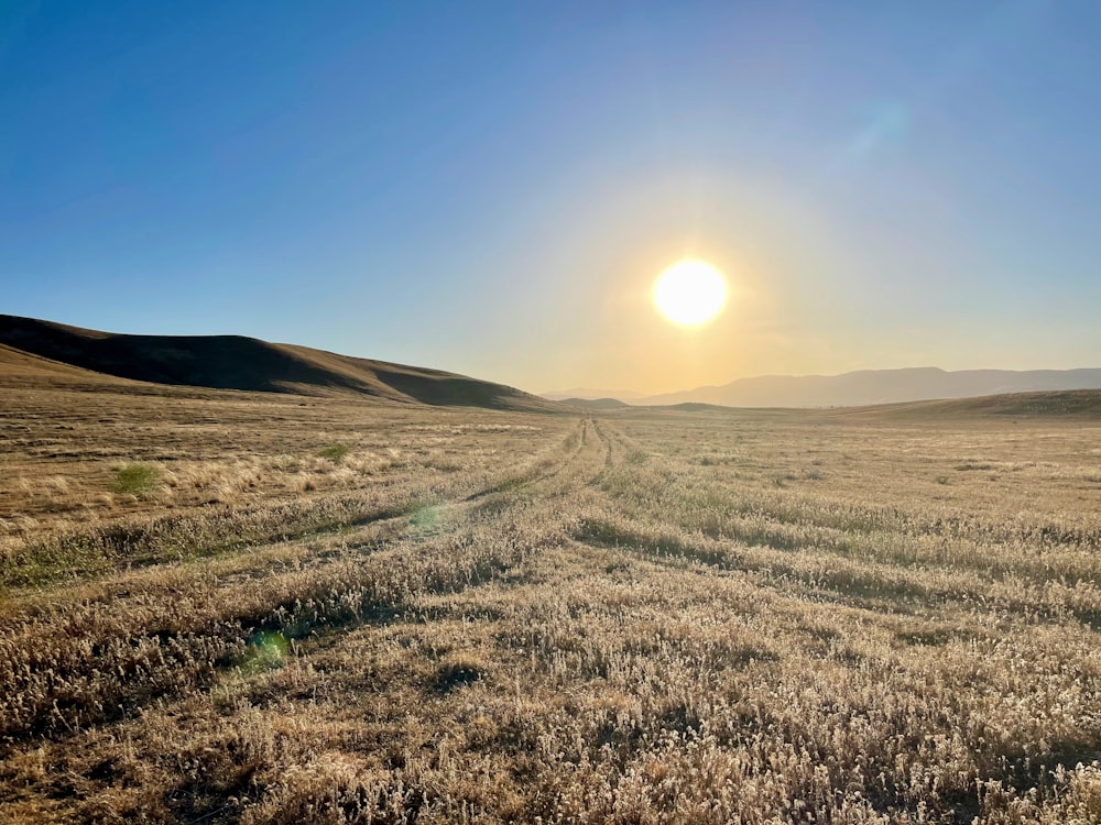 the sun is setting over a wide open field