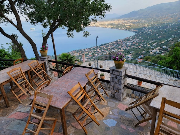 A cozy terrace with a dining set overlooking the Mediterranean coastline under a clear blue sky.