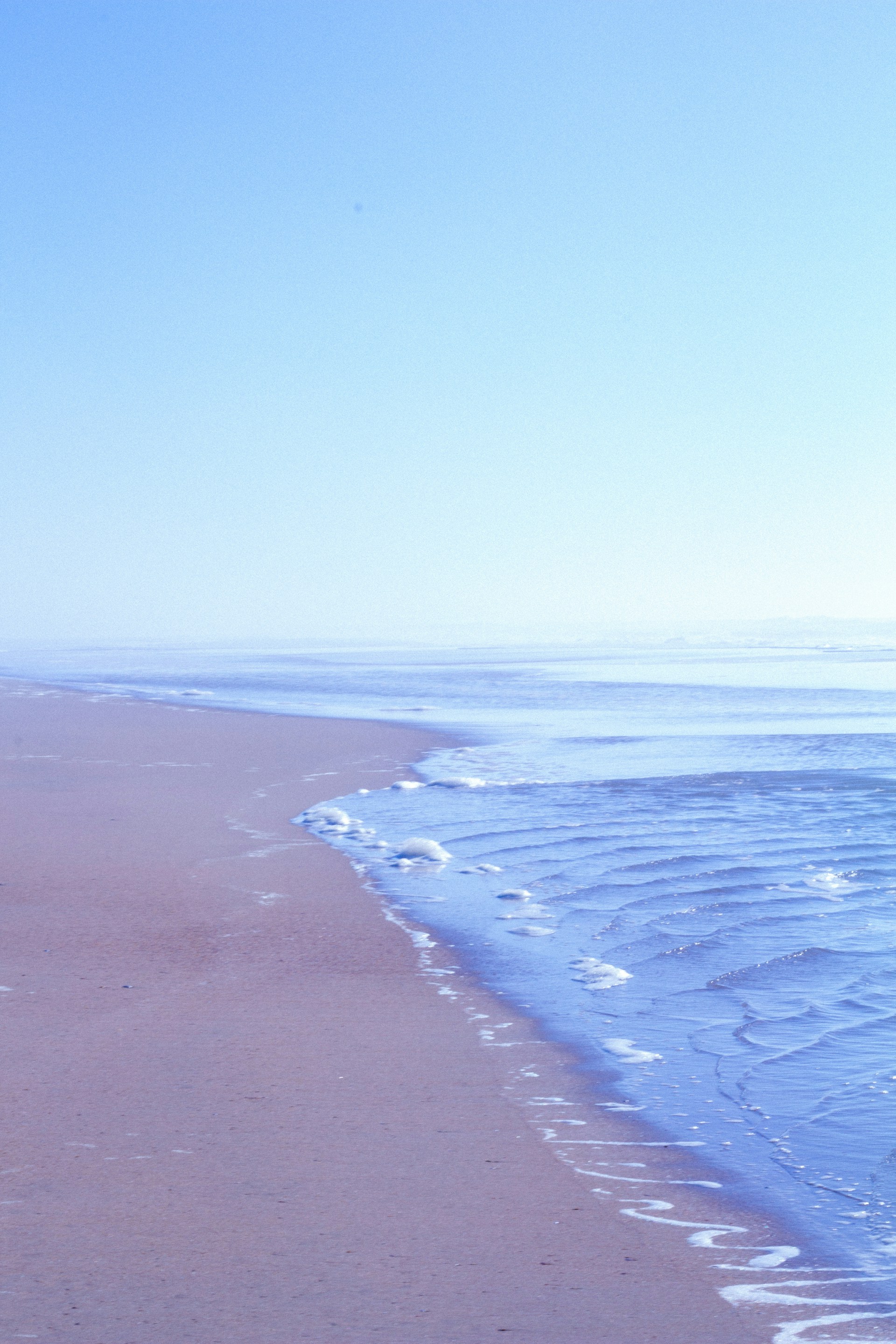 a person walking along a beach with a surfboard