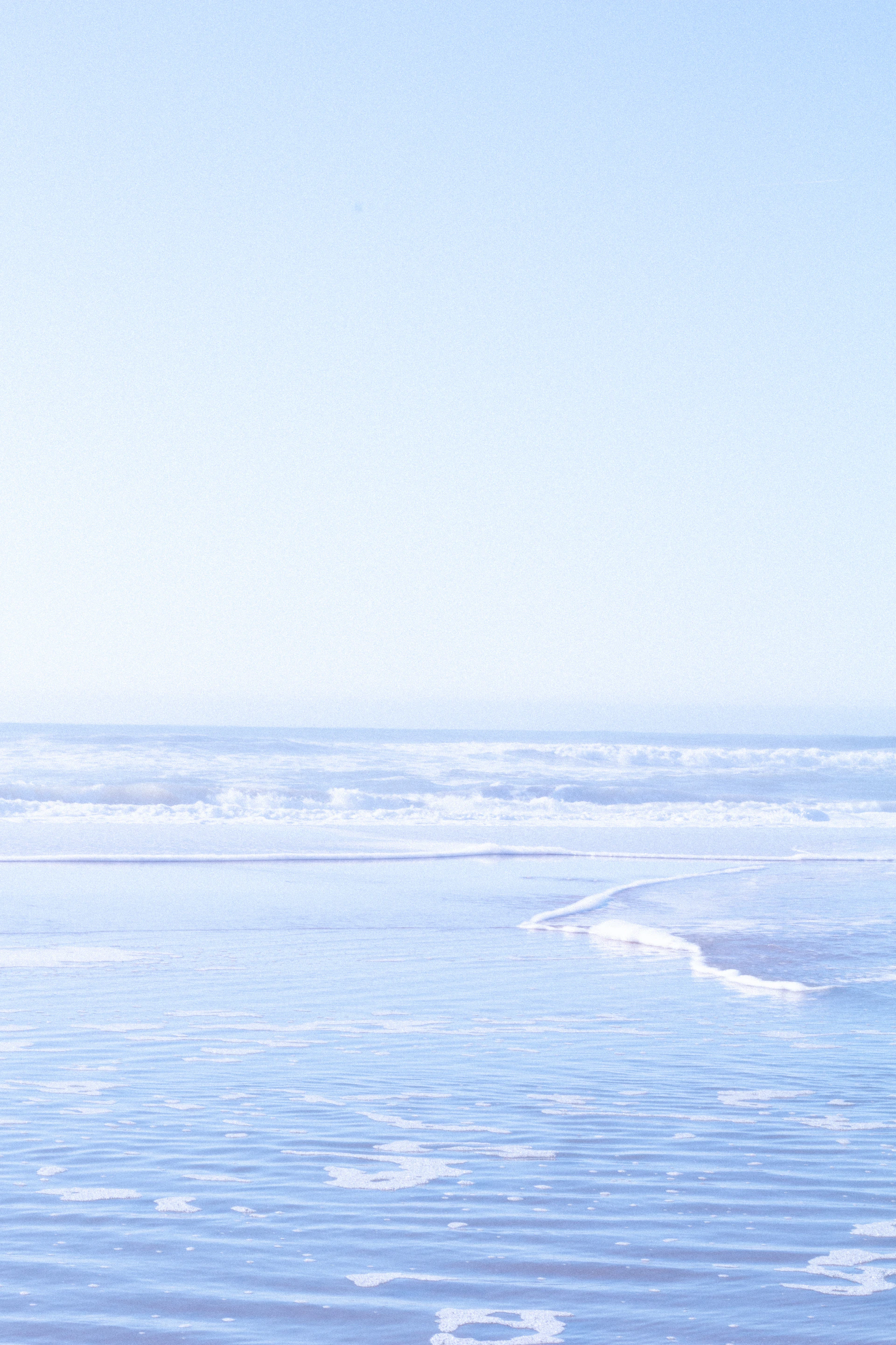 a person walking on the beach carrying a surfboard