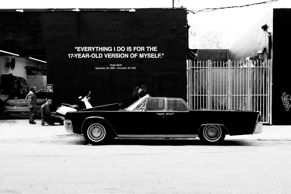 a black and white photo of a car parked in front of a building