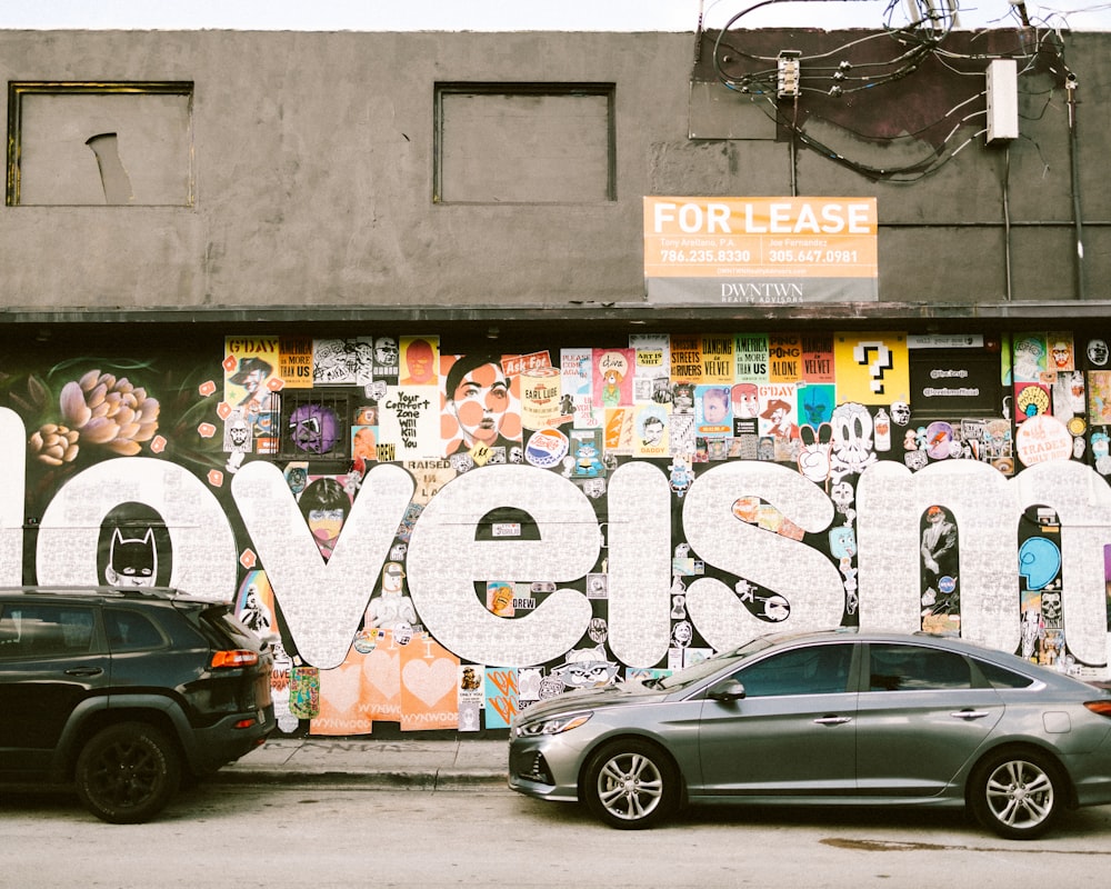 two cars parked in front of a building with graffiti on it