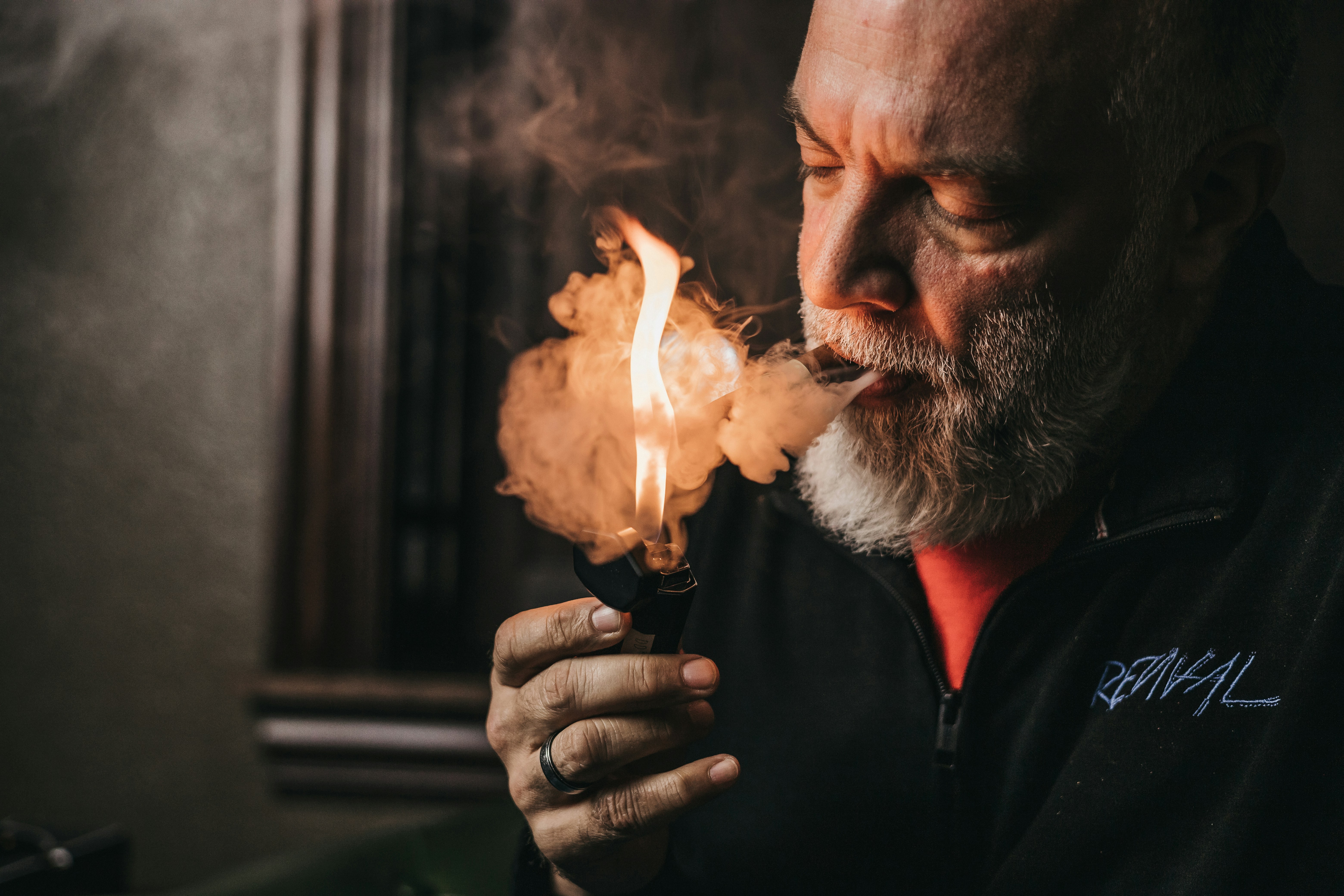a man with a beard holding a lighter in his hand, 