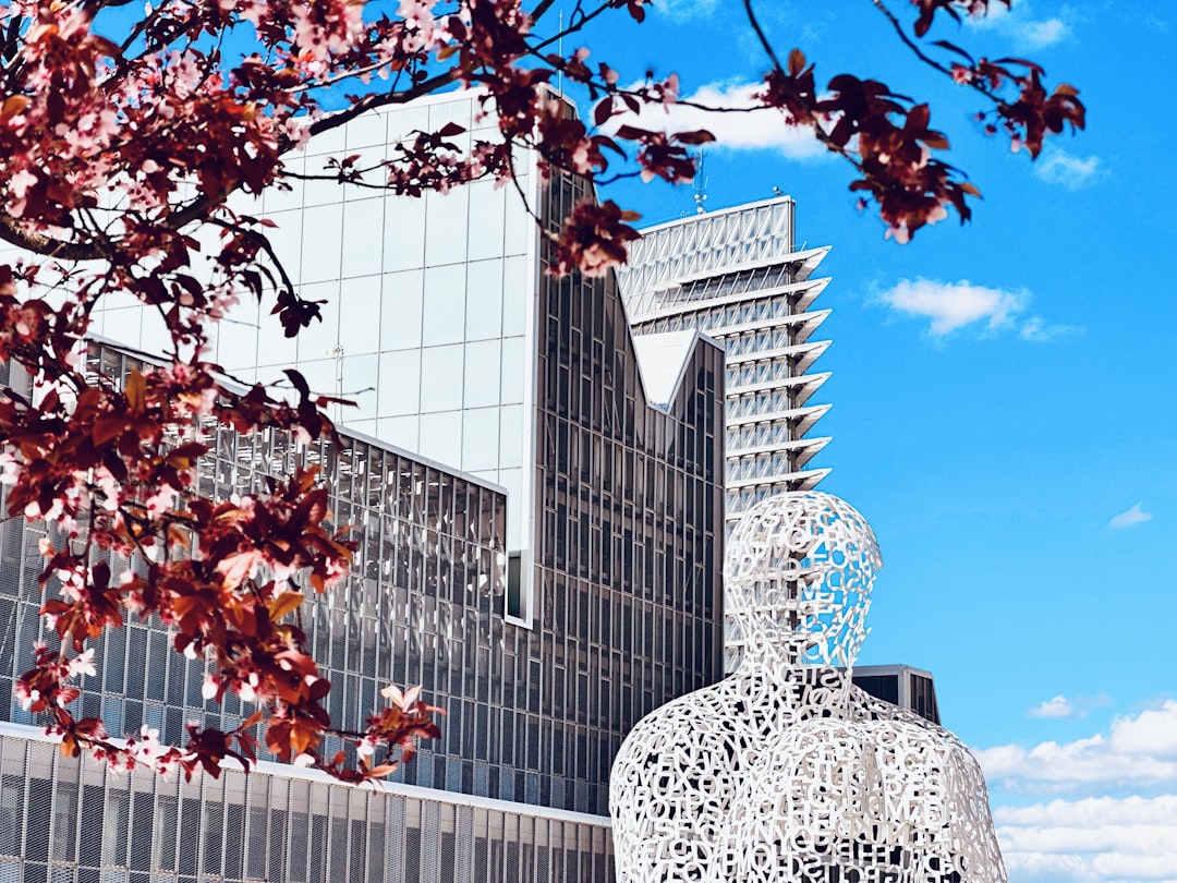 a tall building with a sculpture in front of it, Modern delivery