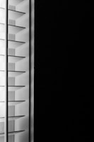 A close-up view of window blinds with horizontal slats, partially open, allowing minimal light to pass through against a dark background.