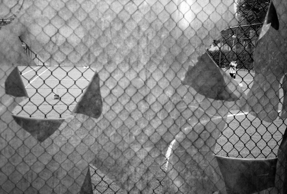 a black and white photo of a baseball field through a chain link fence