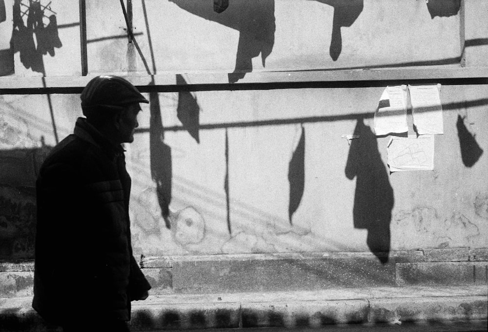 a man walking down a street next to a wall