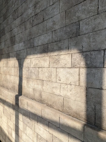 An artistic shot of a stone coping stone casting a shadow on a textured wall during golden hour.