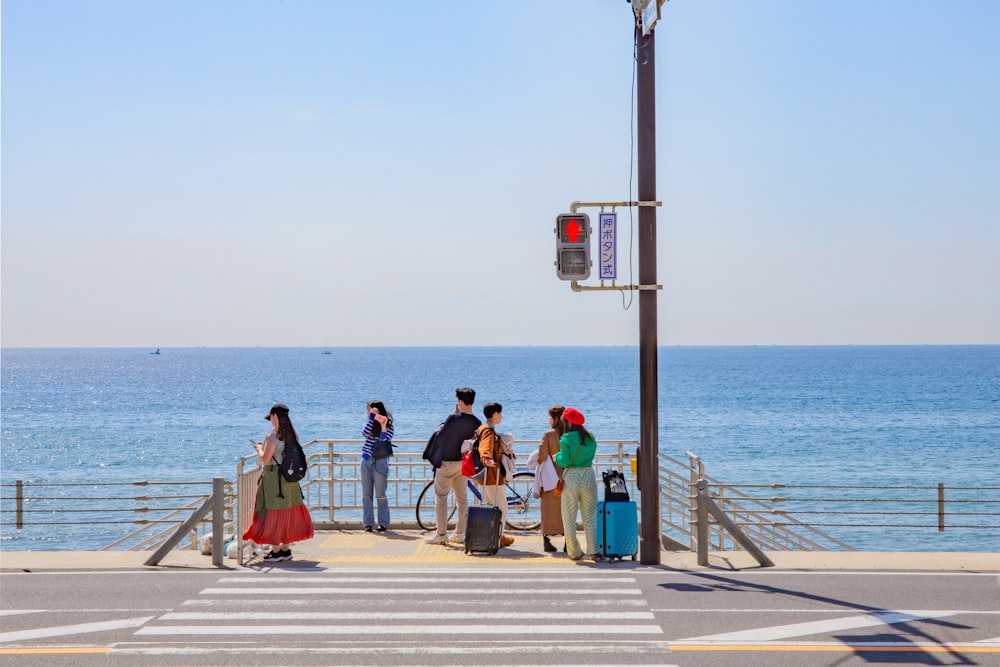 a group of people standing on a pier next to the ocean