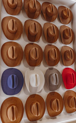 A grid display of various custom hats and vests arranged neatly on a clean white surface.