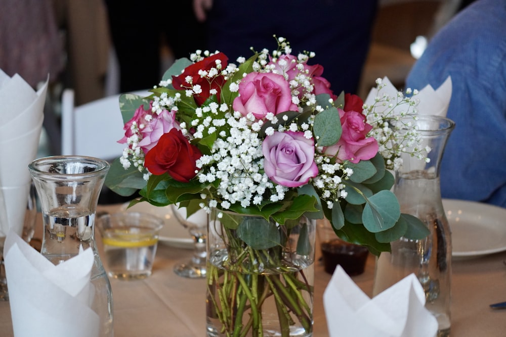 a vase filled with pink and red roses on a table
