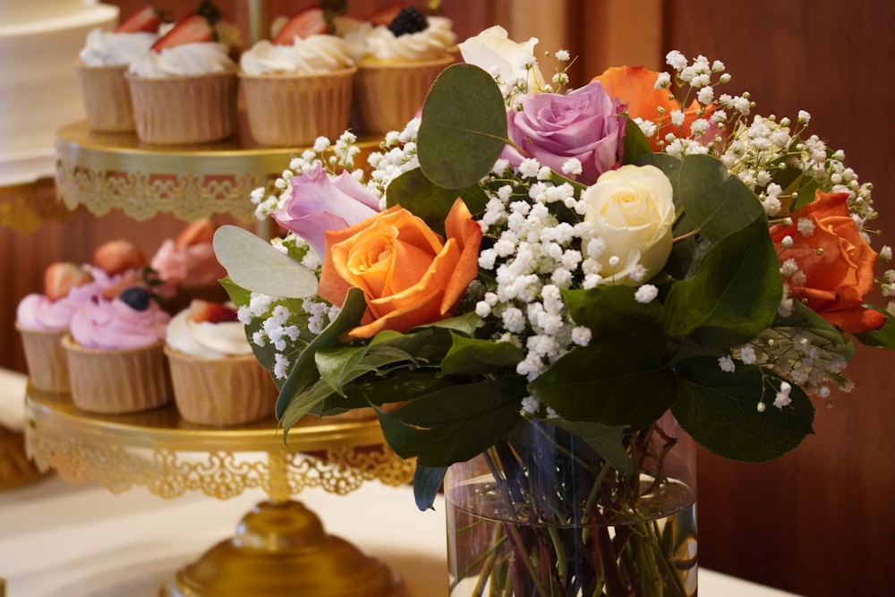 a vase filled with lots of cupcakes on top of a table