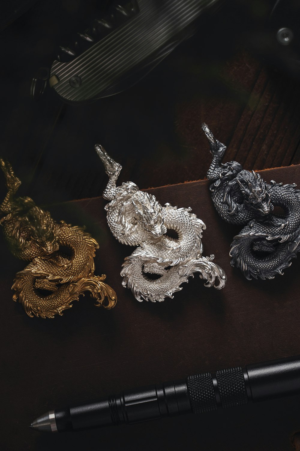 a pen sitting next to three dragon brooches