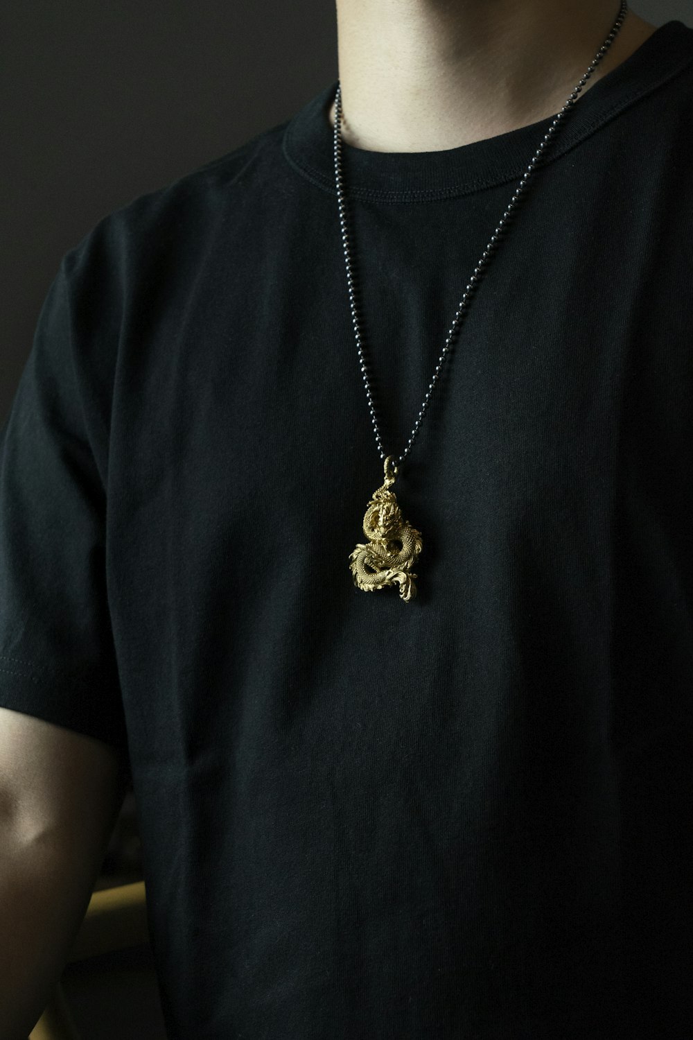 A guest wears gold chain necklaces, a black shirt, a black embossed News  Photo - Getty Images